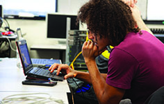 A Computer Information Technology  Program student monitors computer networks on a laptop