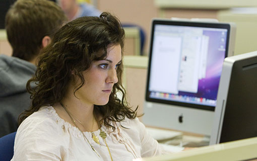 A female NMC student looking into a computer screen
