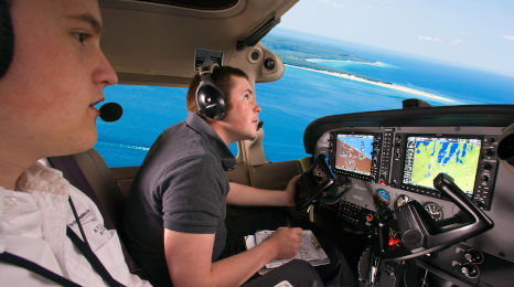 An NMC Aviation program instructor and student in the cockpit of a plane flying over Grand Traverse Bay