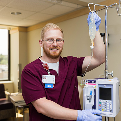 An NMC nursing student in a hospital adjusting an IV bag