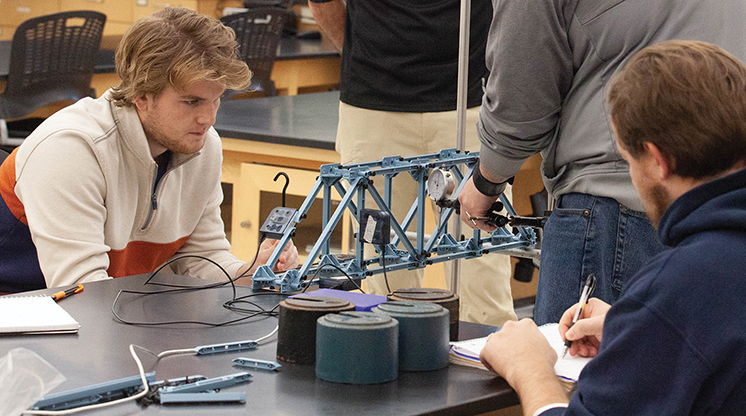 NMC engineering program students and instructor test a bridge model