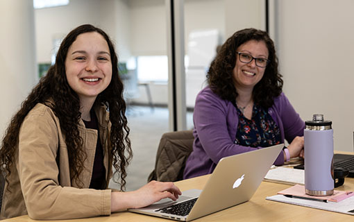 Photo of a smiling NMC student and a student services advisor in a conference room